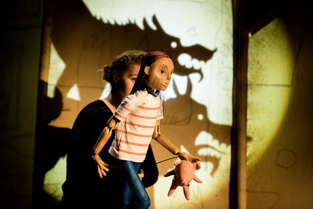 Lucy creeps through the house with pig puppet (image by Dan Tsantilis via the Little Angel Theatre, London)